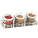 A Cal-Mil stainless steel horizontal display with three hinged glass jars holding nuts and berries.