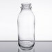 A Libbey clear glass milk bottle with a lid on a table.