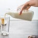 A hand pouring milk into a Libbey glass.