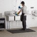 A man standing in a Regency 3 compartment sink with a drainboard.