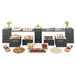A rectangular bamboo riser shelf on a table with different food items.