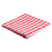 A folded red and white checkered Intedge vinyl table cover on a table.