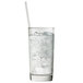 A close up of an Arcoroc beverage glass filled with ice water and a straw.