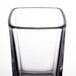 A close up of an Arcoroc clear tall square shot glass with a black rim.