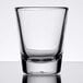 An Arcoroc clear shot glass on a white surface.