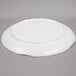 A Tablecraft white round melamine tray with a pebbled rim on a gray surface.