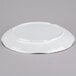 A Tablecraft white round melamine tray with a pebbled rim on a gray surface.