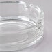 A clear Arcoroc glass ashtray with a small hole in the center.