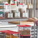 A person reaching for a shelf with clear label holders holding containers of food.