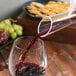 A person pouring a glass of wine into a Chef & Sommelier decanter.