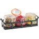 A black metal tray with three glass jars with black lids filled with different food.
