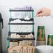 A black stair step condiment display with glass jars holding coffee condiments.