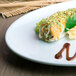 A sushi roll with sauce and vegetables on a Thunder Group Blue Jade oval melamine platter.