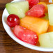 An Arcoroc Rondo bowl filled with cherries and grapes on a table.