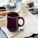 A brown Tuxton China Princess mug filled with coffee on a table with a spoon.