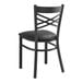 A Lancaster Table & Seating black metal cross back chair with a black vinyl cushion.