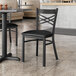 A Lancaster Table & Seating black metal chair with a black cushion on a table in a restaurant.