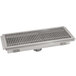 A stainless steel floor water receptacle with a metal grate over a drain.