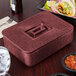 A red HS Inc. multi-purpose container with a lid on a table with food and drinks.