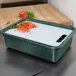 A white HS Inc. plastic tote container filled with food on a tray.
