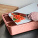 A person cutting tomatoes on an HS Inc. paprika cutting board.