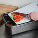 A person using a HS Inc. charcoal cutting board to chop tomatoes on a counter.