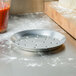 An American Metalcraft heavy weight aluminum pizza pan with holes in it sitting on a counter.