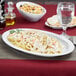 A white oval platter with pasta, shrimp, and vegetables on it.