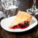 A slice of pie on a Tuxton AlumaTux china plate with a glass of wine.