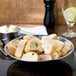 An American Metalcraft hammered stainless steel bowl filled with bread on a table.