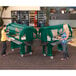 A green Cambro food cart with food on it being used outdoors by two women.