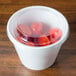 A Dart clear plastic dome lid on a plastic container of tomatoes.