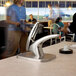 A woman using a San Jamar FrontLine In Counter Condiment Dispenser System over a sink in a cafeteria.