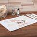 A table set with Hoffmaster Four Faiths paper placemats, a knife, and food.