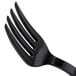 A close-up of a WNA Comet Classicware EcoSense black plastic fork.