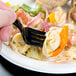 A black WNA Comet EcoSense plastic fork in a plate of food.