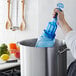 A hand holding a San Jamar blue Rapi-Kool cooling paddle and pouring liquid into a silver pot.