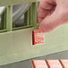 A single-use dishwasher temperature test label being applied to a dish rack.