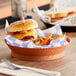 A terracotta plastic round basket filled with a cheeseburger and fries.