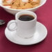 An Arcoroc stack cup filled with coffee on a saucer.