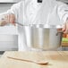 A chef holding a Vollrath Wear-Ever sauce pan on a wooden table.