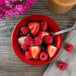 A Tuxton cayenne china fruit dish filled with strawberries and a fork.