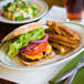 A Tuxton oval china platter with a burger and fries on it.
