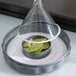 a glass cone with a round container with lime slices