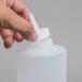 A close-up of a person's hand holding a white Tablecraft squeeze bottle.