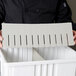 A person holding a Long Metro gray tote box divider with a row of holes.