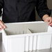 A person holding a Long Metro gray tote box divider with food.