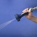 A hand holding a T&S pre-rinse spray valve with blue and silver accents.