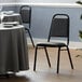 A table set with a black Lancaster Table & Seating banquet chair with a black cushion.