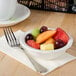 A bowl of fruit in a white scalloped edge china bowl.